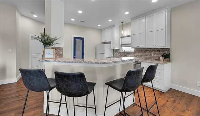 a kitchen with stainless steel appliances kitchen island granite countertop a dining table chairs and white cabinets
