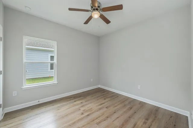an empty room with a window and a ceiling fan