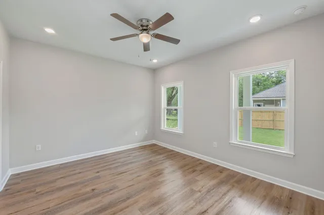 an empty room with wooden floor and windows