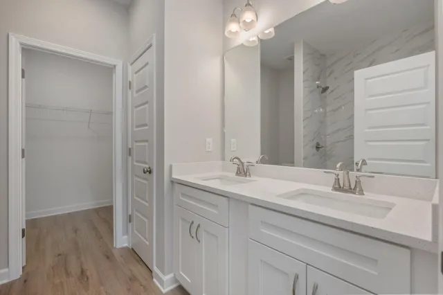 a bathroom with a double vanity sink a mirror and a shower