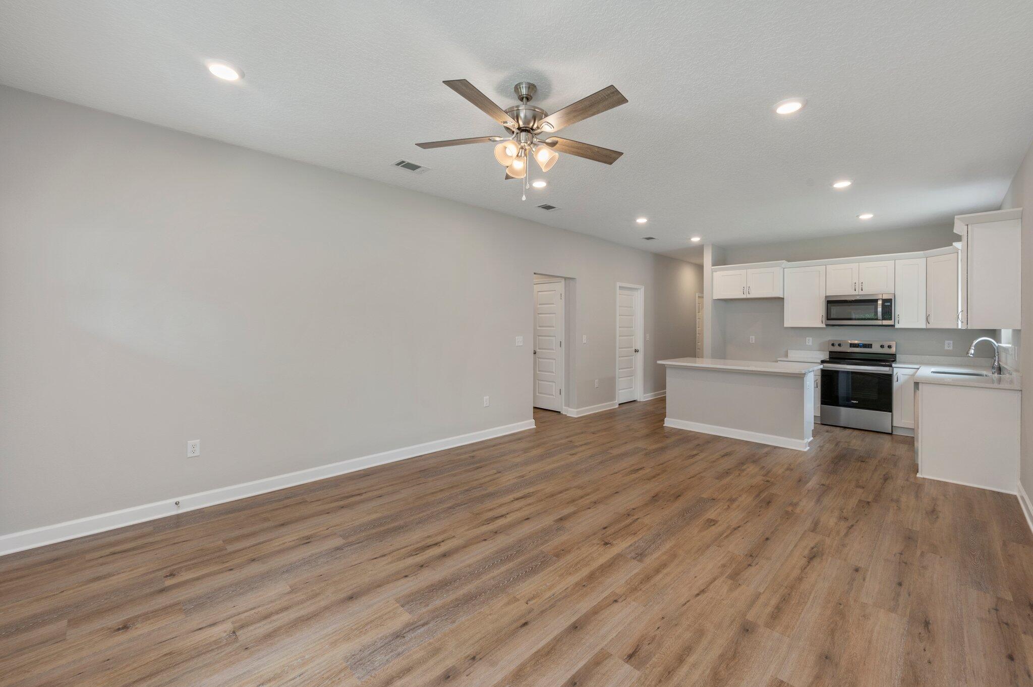 95 Live Oak Street Freeport, FL 32439 - Photo 6 of 26 a view of an empty room with wooden floor and a ceiling fan