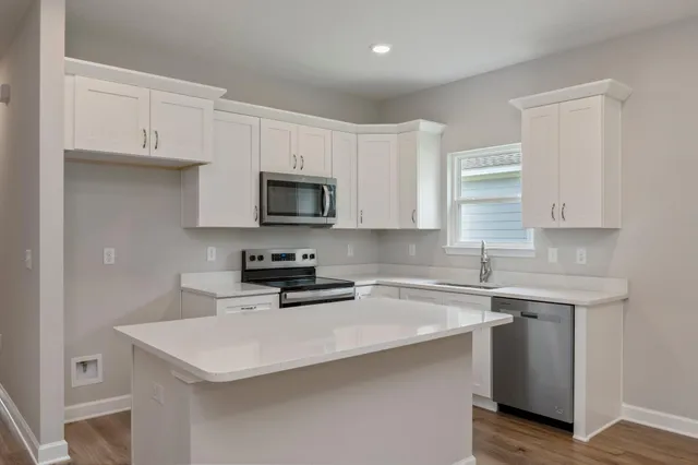 a kitchen with stainless steel appliances a sink a stove a microwave a center island and cabinets