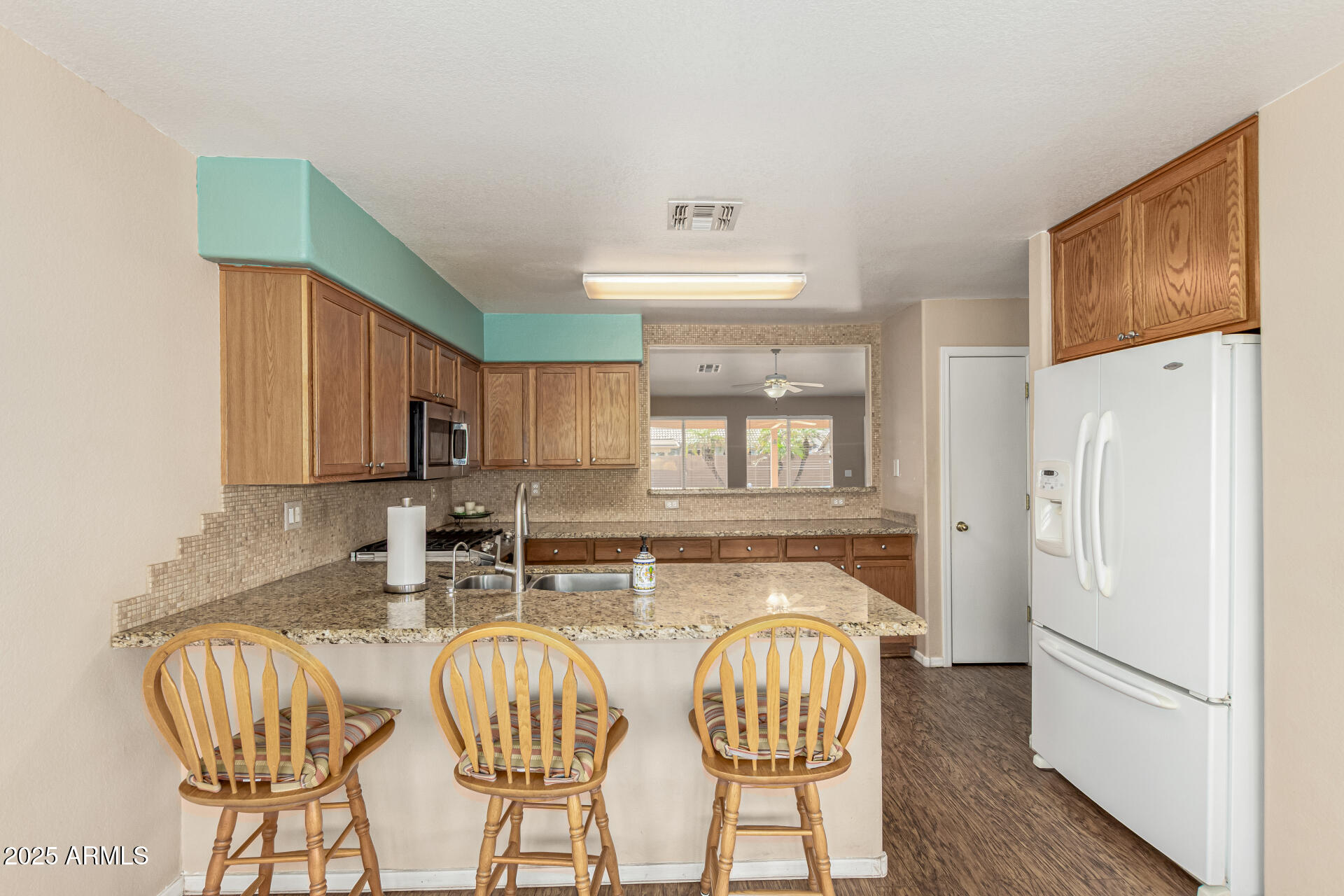 823 West 14th Avenue Apache Junction, AZ 85120 - Photo 12 of 32 a kitchen with stainless steel appliances granite countertop a refrigerator a sink a stove a dining table and chairs