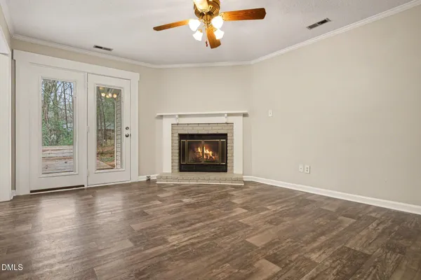 a view of an empty room with wooden floor fireplace and a window
