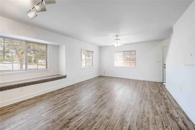 an empty room with a window and a ceiling fan