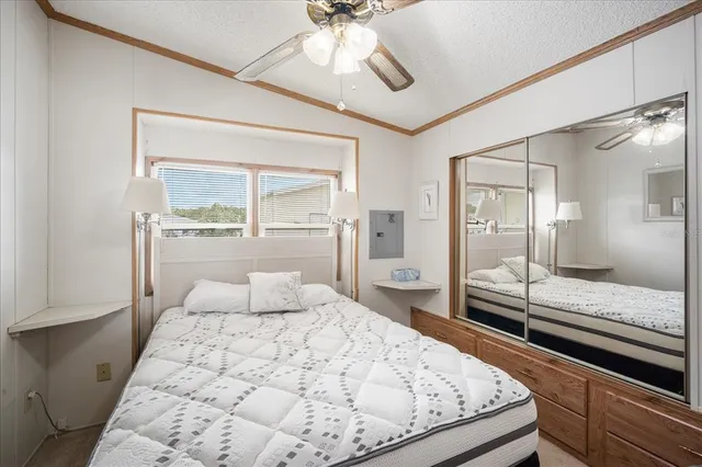 a bedroom with a large bed and a chandelier fan