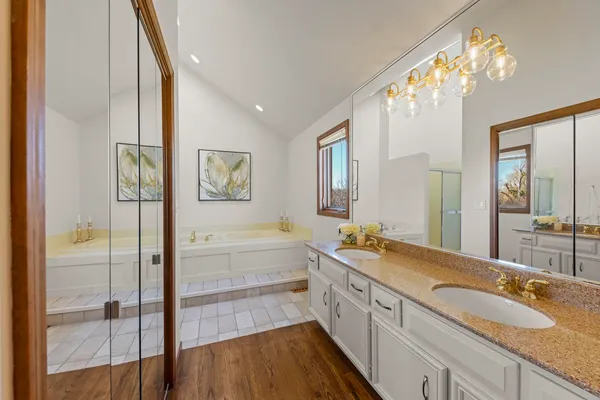 a spacious bathroom with a granite countertop tub sink a mirror a shower and vanity