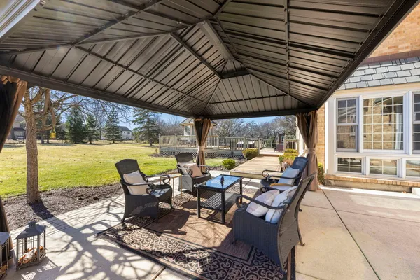 a view of a patio with lawn chairs and couches with wooden floor and roof with floor to ceiling window