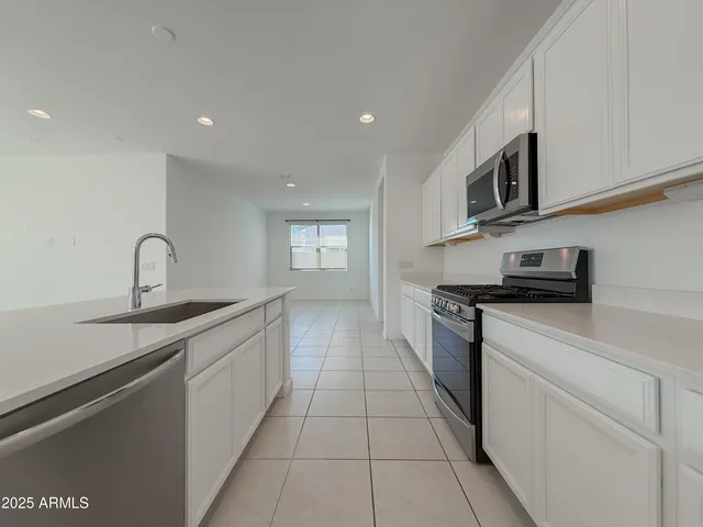 a kitchen with white cabinets a sink and white appliances