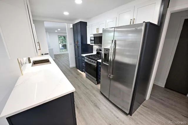 a kitchen with metallic refrigerator a sink and wooden floor