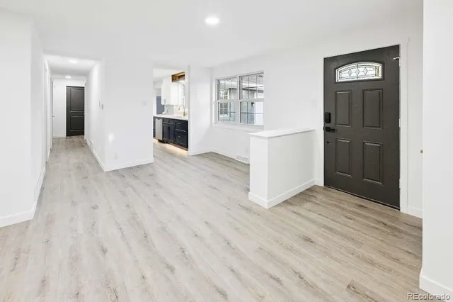 an empty room with wooden floor and a kitchen