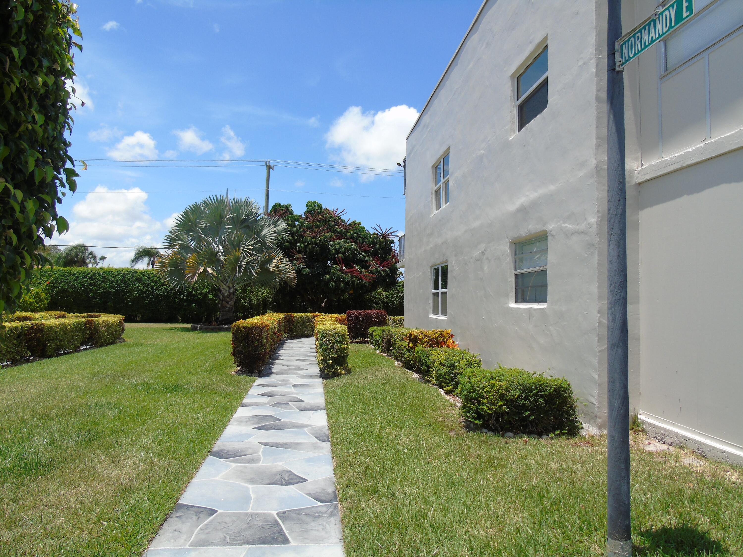 219 Normandy Lane Delray Beach, FL 33484 - Photo 24 of 33 a front view of a house with a yard and potted plants
