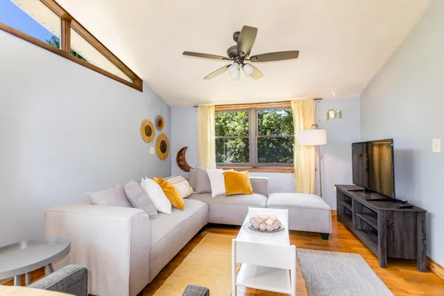 a living room with furniture a potted plant and a large window