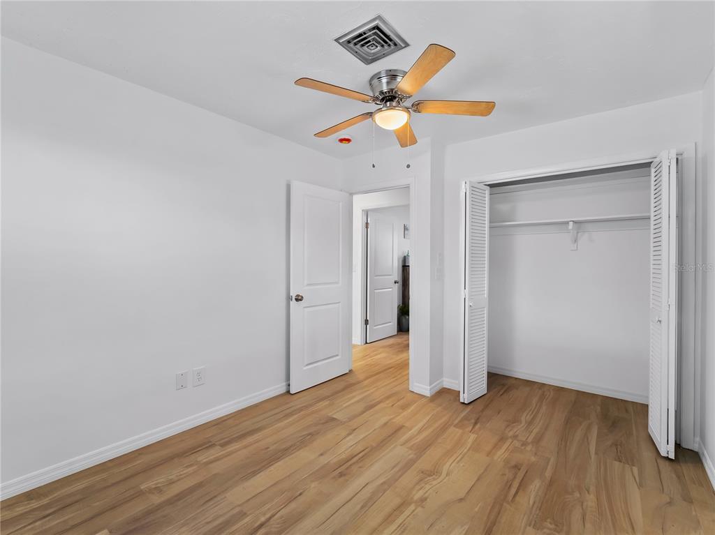 116 The Corso, Unit 116 Venice, FL 34285 - Photo 22 of 36 an empty room with wooden floor and a ceiling fan