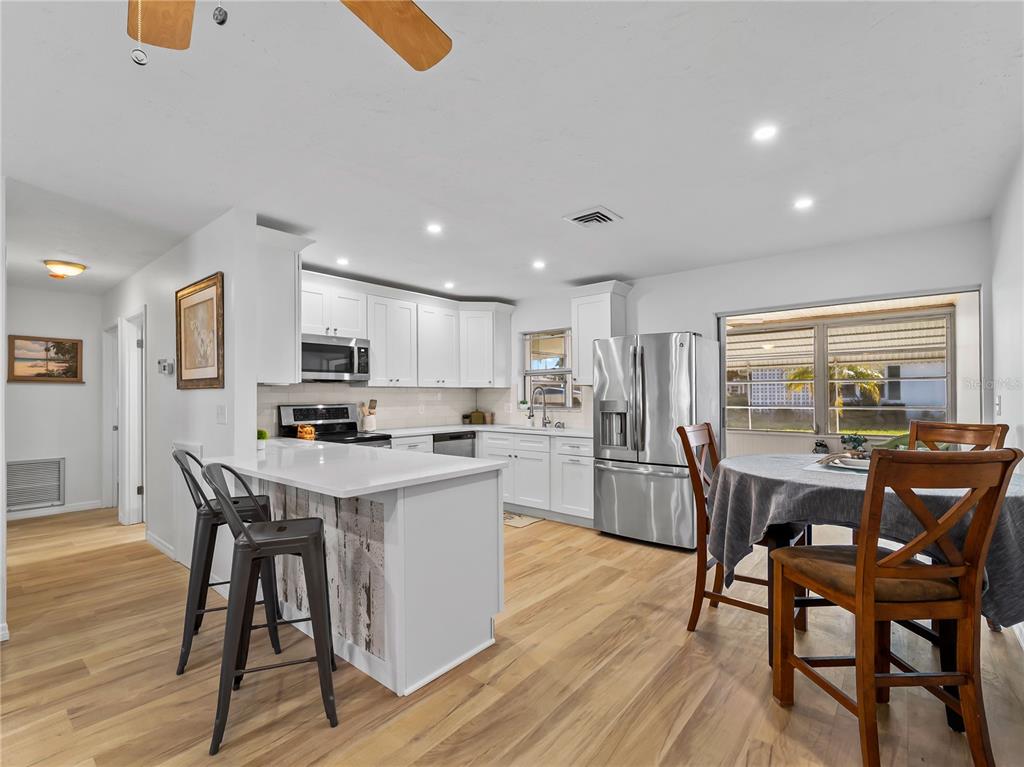 116 The Corso, Unit 116 Venice, FL 34285 - Photo 9 of 36 a kitchen with stainless steel appliances kitchen island granite countertop a table chairs and a refrigerator