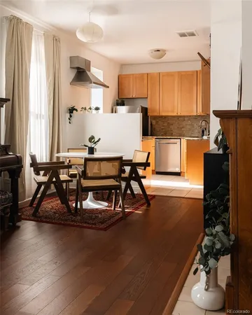 a view of a kitchen with kitchen island stainless steel appliances wooden floor dining table and chairs