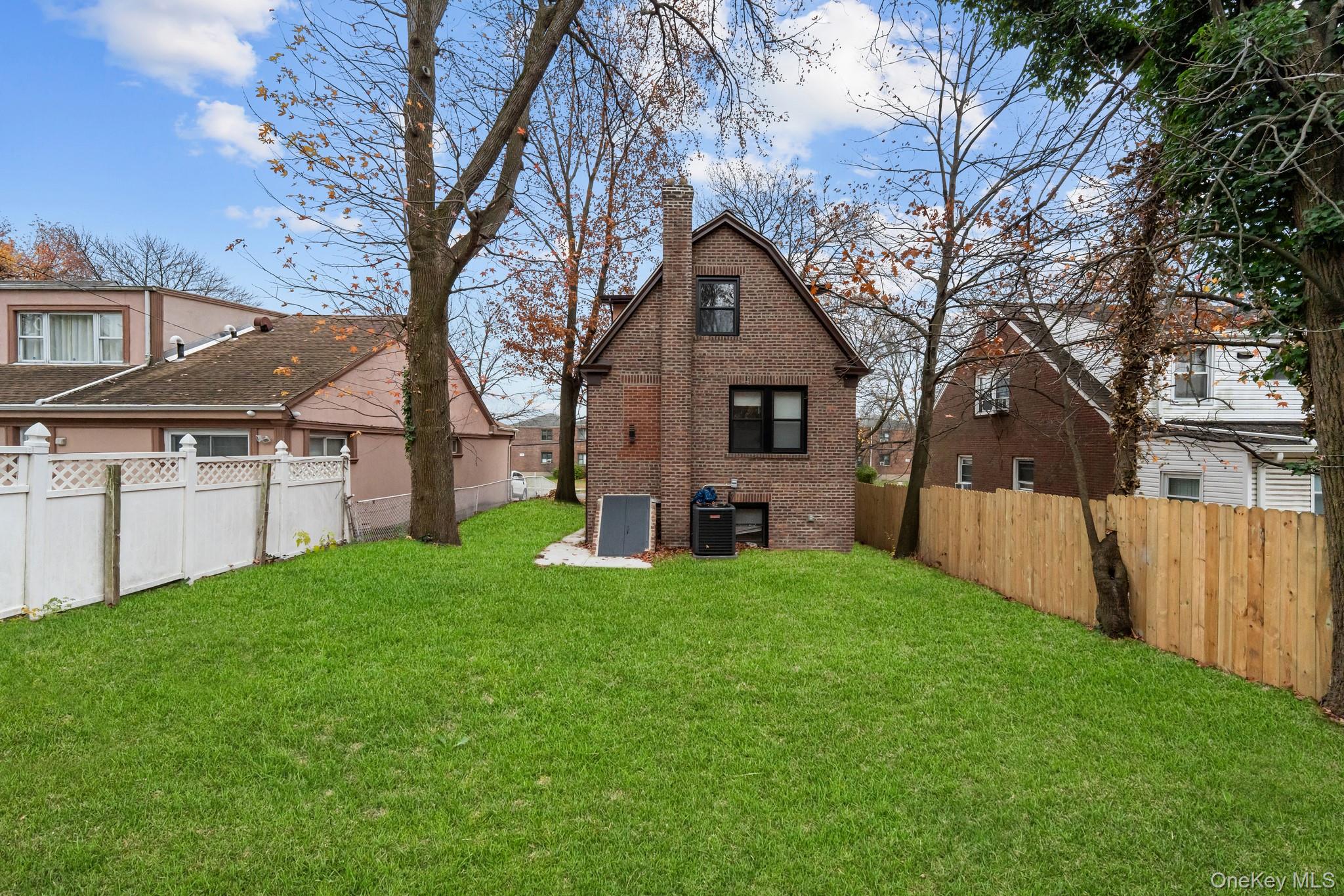 218-37 Spencer Avenue Queens, NY 11427 - Photo 12 of 31 Rear view of house featuring a chimney, a fenced backyard, and brick siding