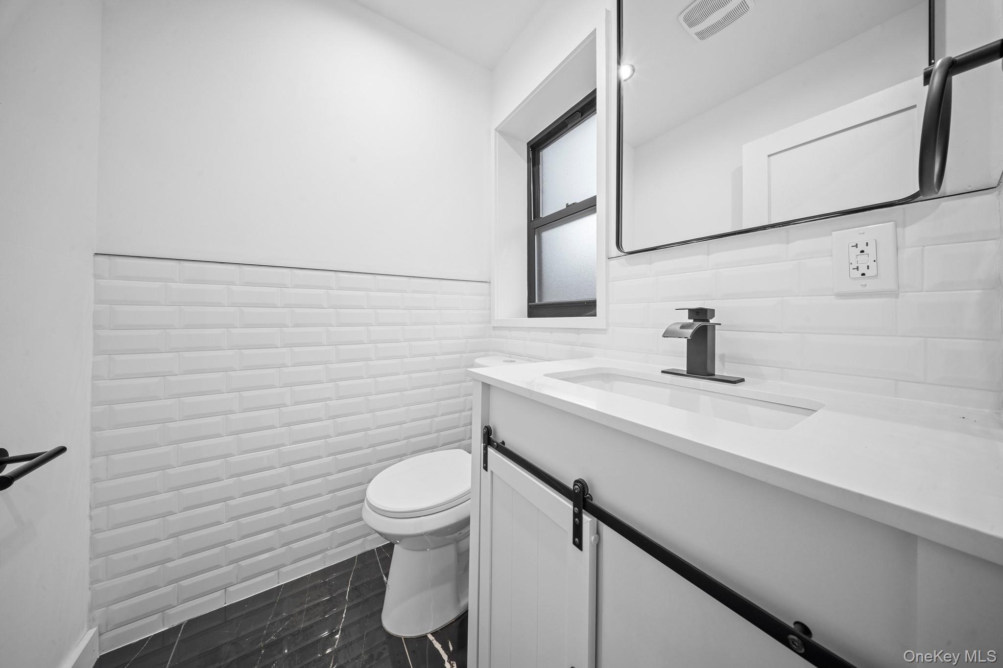 218-37 Spencer Avenue Queens, NY 11427 - Photo 15 of 31 Bathroom featuring vanity, tile walls, and wainscoting