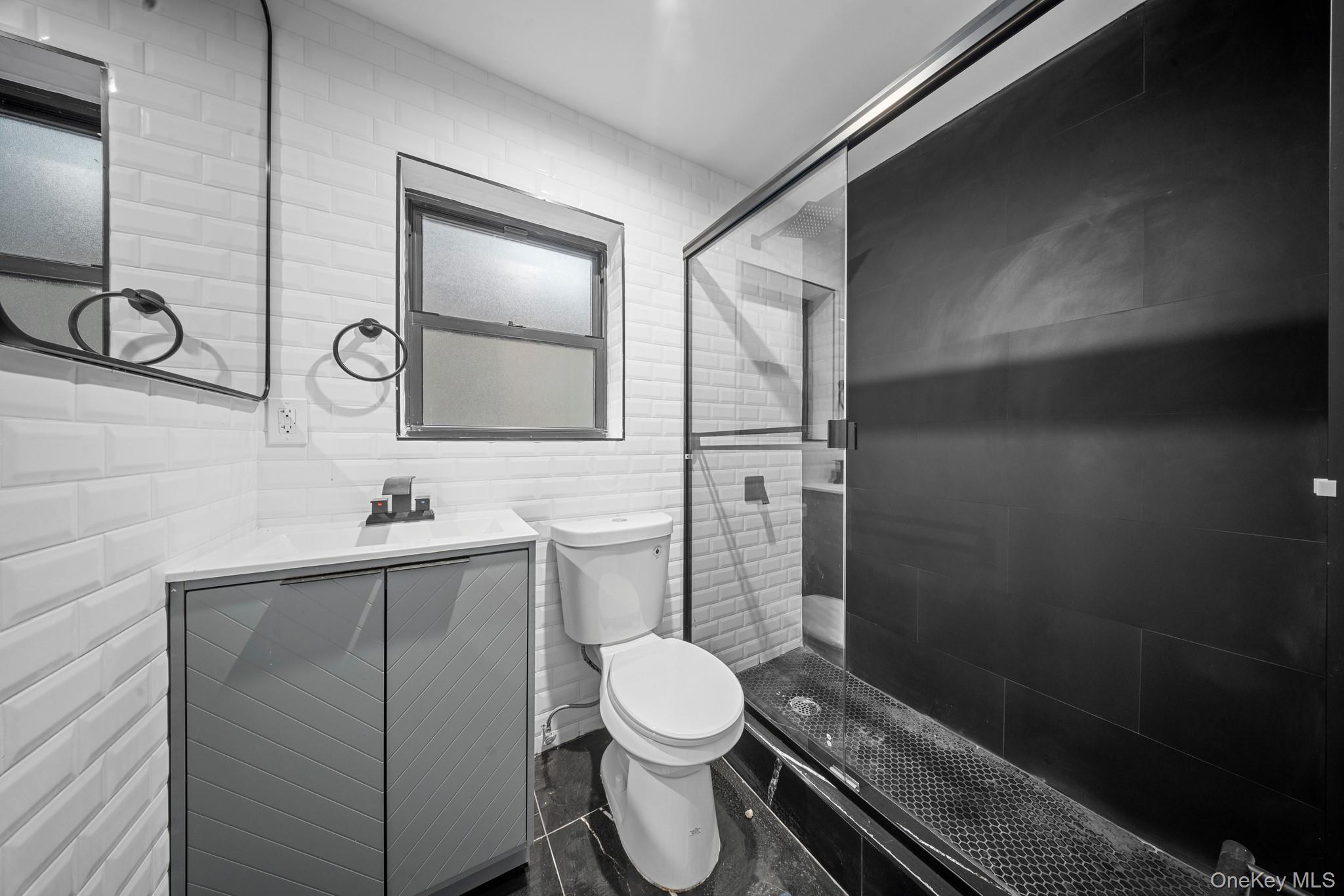 218-37 Spencer Avenue Queens, NY 11427 - Photo 17 of 31 Full bath with vanity, a stall shower, and tile walls