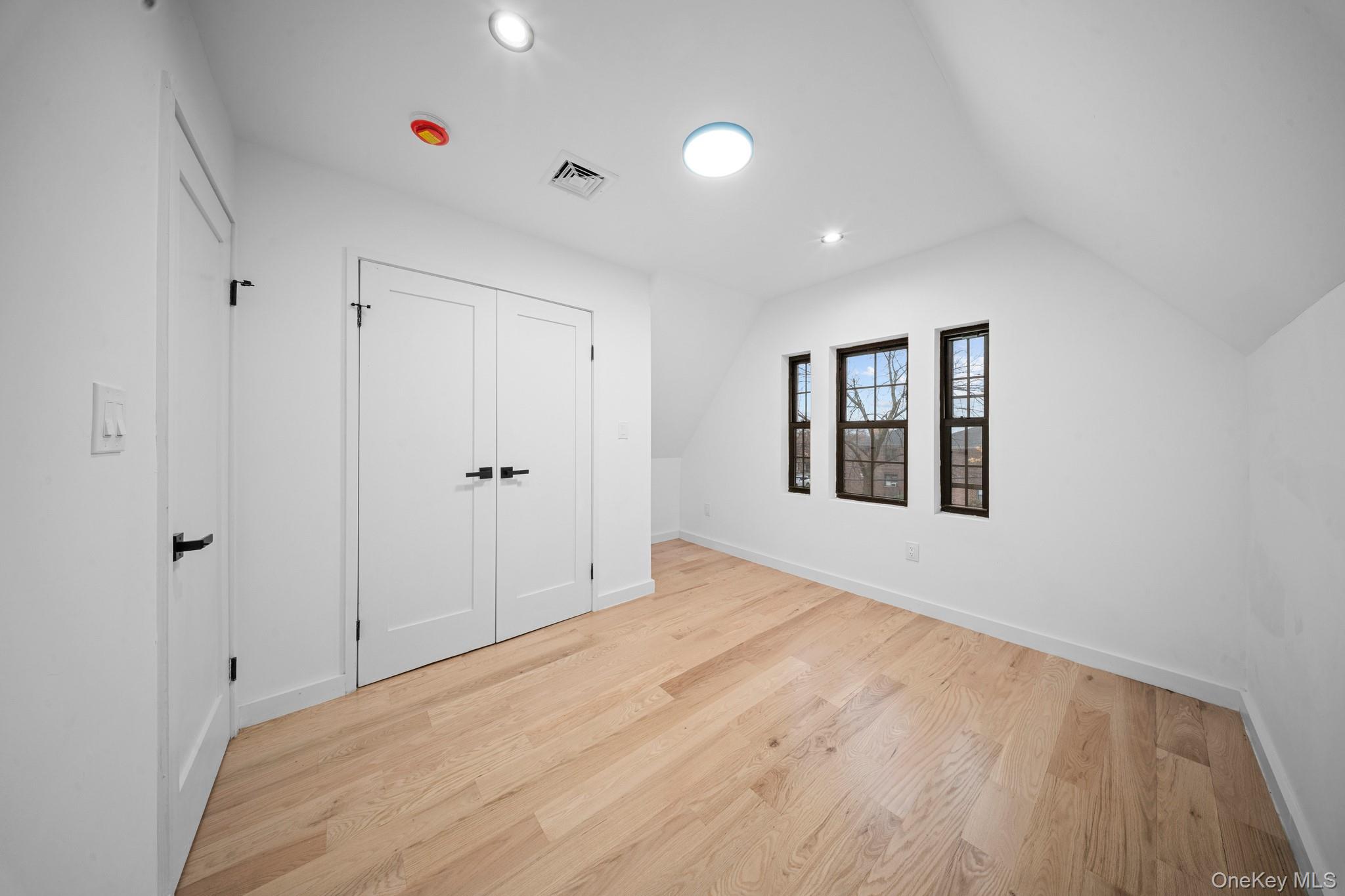 218-37 Spencer Avenue Queens, NY 11427 - Photo 23 of 31 Unfurnished bedroom featuring light wood-style flooring, lofted ceiling, a closet, and recessed lighting