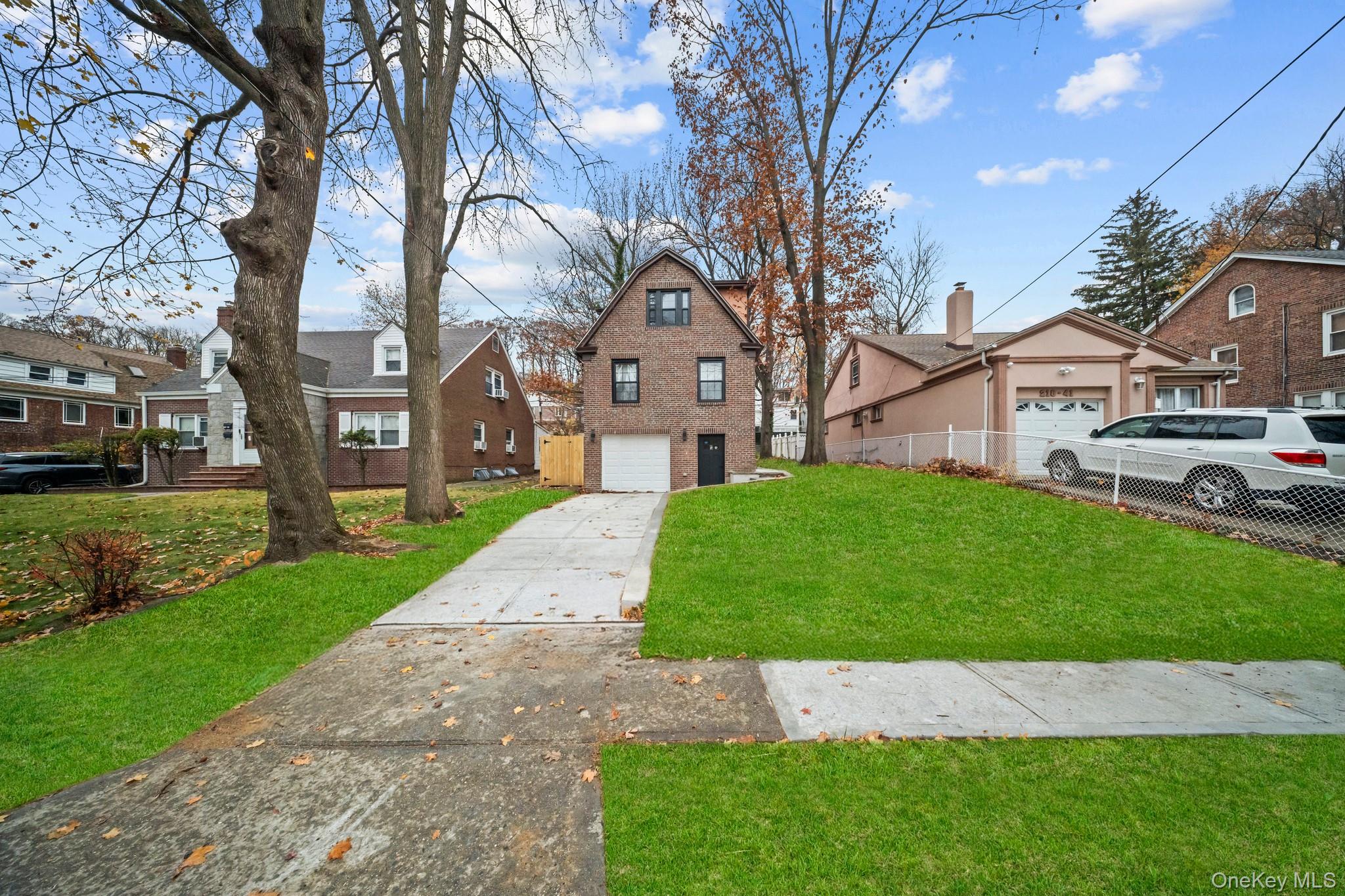 218-37 Spencer Avenue Queens, NY 11427 - Photo 26 of 31 View of front of house featuring driveway, a residential view, a front yard, and brick siding