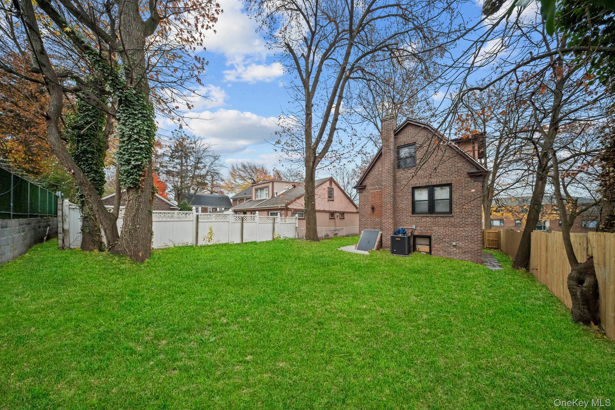 218-37 Spencer Avenue Queens, NY 11427 - Photo 28 of 31 Back of property featuring a fenced backyard, a chimney, and brick siding