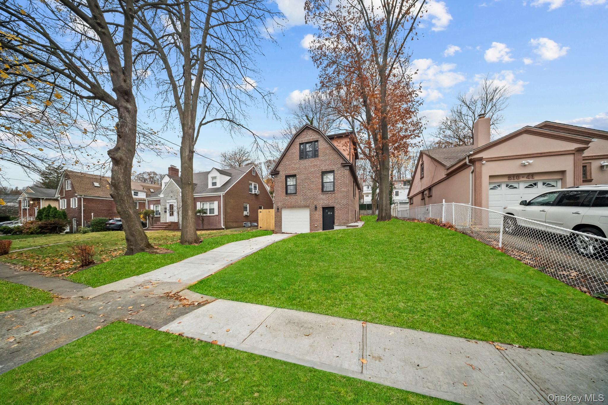 218-37 Spencer Avenue Queens, NY 11427 - Photo 31 of 31 View of front of property with a residential view, a garage, a chimney, and driveway