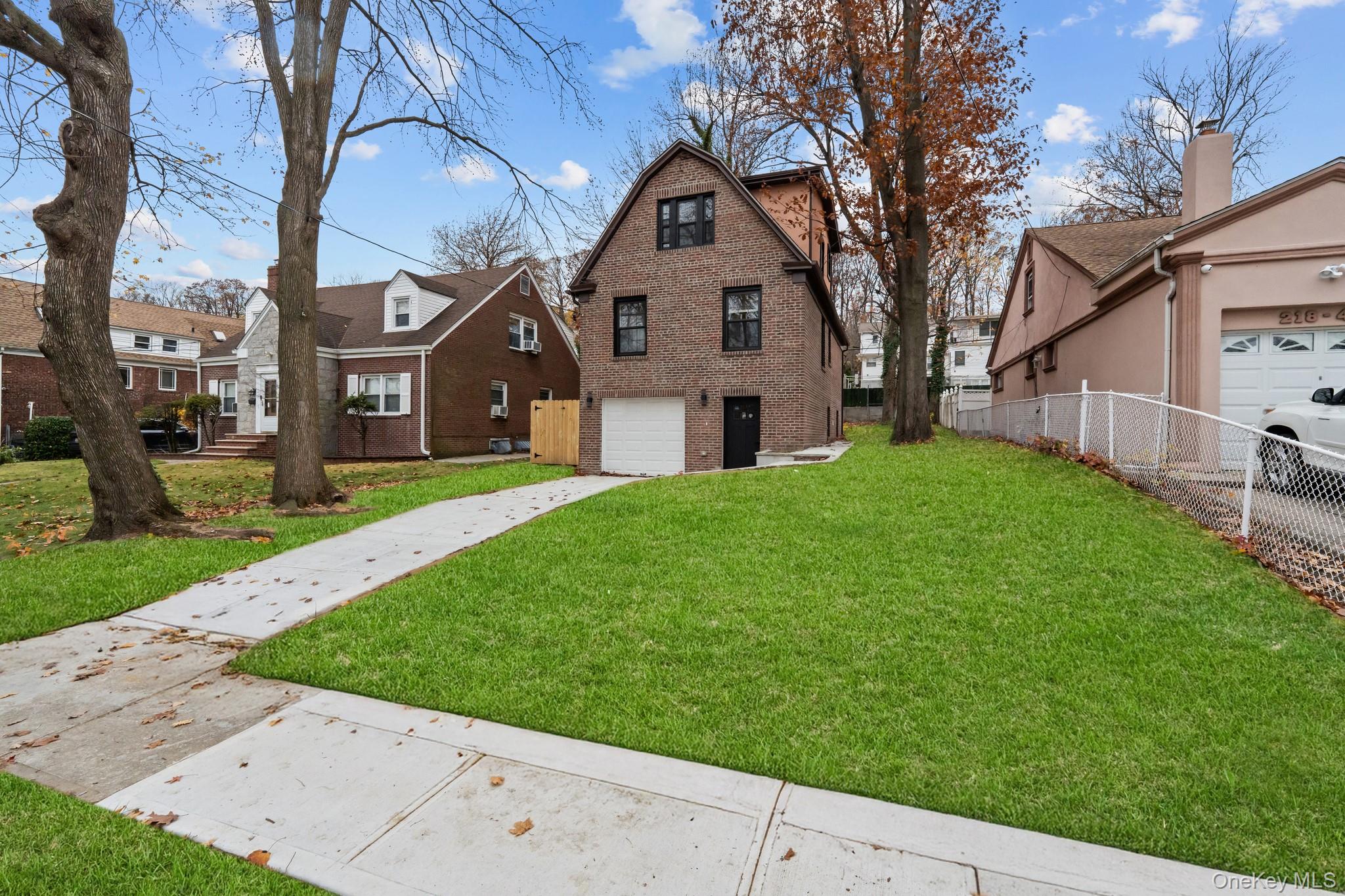 218-37 Spencer Avenue Queens, NY 11427 - Photo 10 of 31 View of front of house featuring driveway, a garage, a residential view, and brick siding