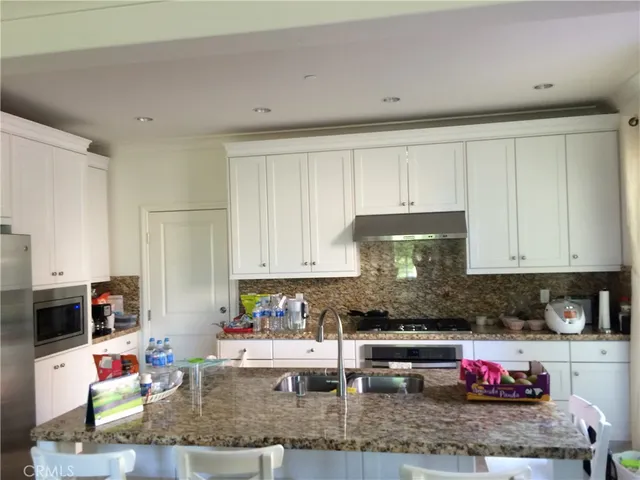 a kitchen with granite countertop a sink and white cabinets