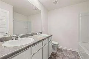 a bathroom with a granite countertop sink a toilet and a mirror