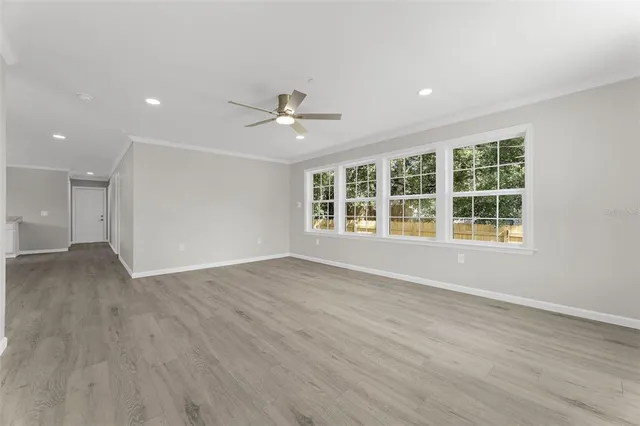 a view of an empty room with a window and wooden floor