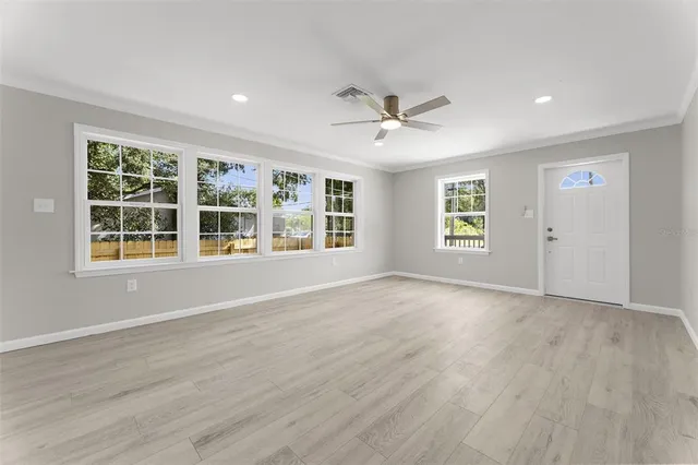 a view of an empty room with a window and wooden floor
