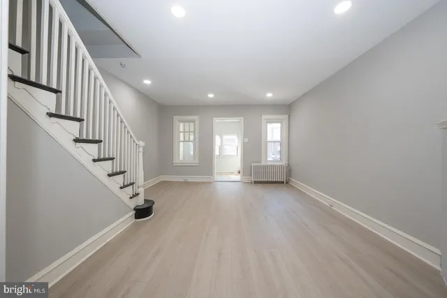 a view of an empty room with wooden floor and stairs