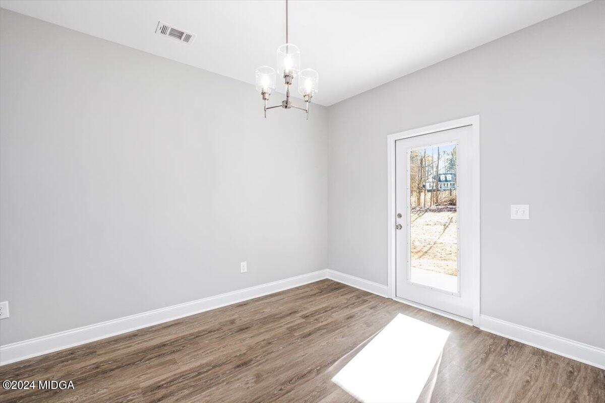 364 Walnut Grove Road Gray, GA 31032 - Photo 11 of 27 an empty room with wooden floor chandelier and windows
