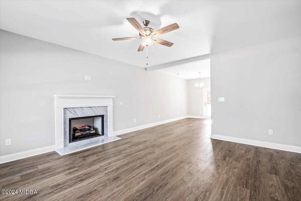 364 Walnut Grove Road Gray, GA 31032 - Photo 4 of 27 an empty room with wooden floor a ceiling fan a fireplace and windows