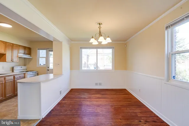 a view of a hallway with wooden floor and a kitchen