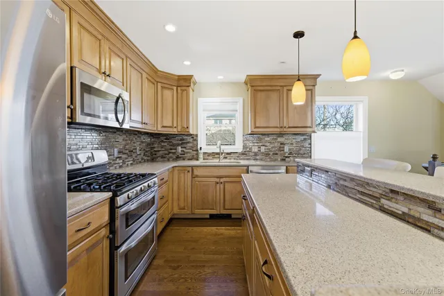 a kitchen with stainless steel appliances granite countertop a kitchen island a stove a sink dishwasher and white cabinets with wooden floor