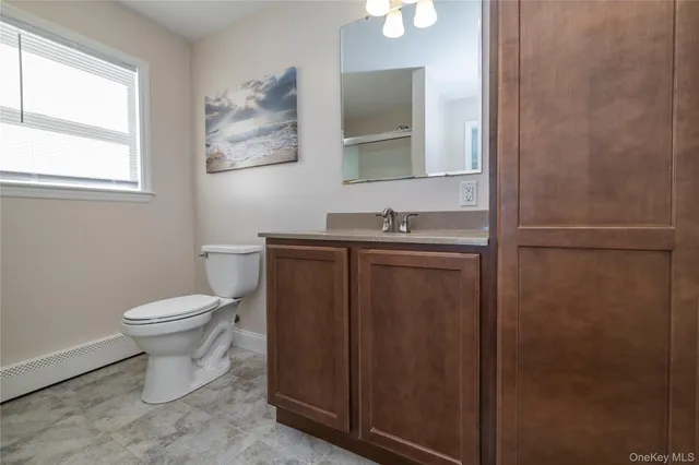 a bathroom with a granite countertop sink a toilet and a mirror