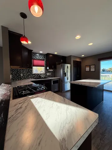 a kitchen with stainless steel appliances kitchen island granite countertop a refrigerator and a stove