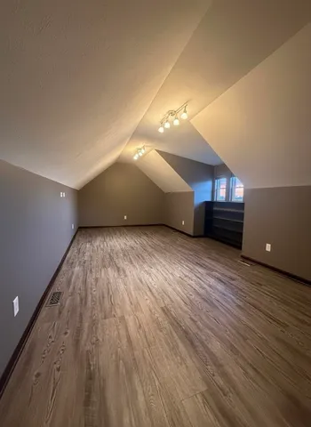 a view of an empty room with wooden floor and window