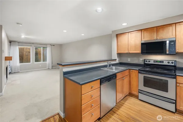 a kitchen with stainless steel appliances granite countertop a stove a sink and a microwave