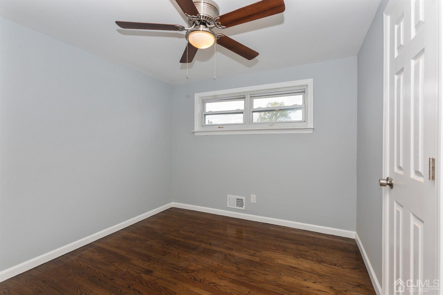 70 Westminster Road Colonia, NJ 07067 - Photo 9 of 12 an empty room with wooden floor ceiling fan and windows