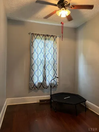 a view of an empty room with wooden floor and a fireplace