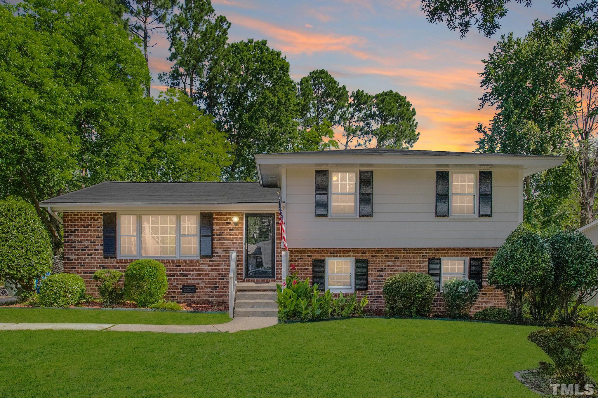 a front view of a house with a yard and green space