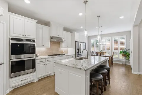 a kitchen with stainless steel appliances granite countertop a stove a sink and a wooden floors