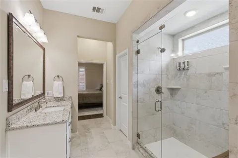 a en suite bathroom with a granite countertop sink a mirror and shower