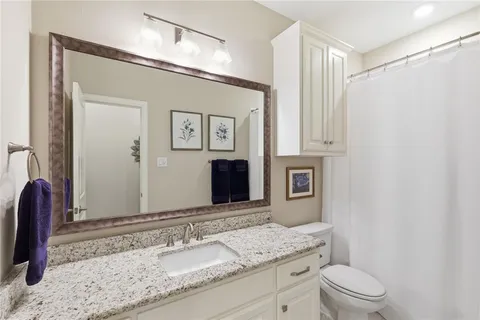a bathroom with a granite countertop sink mirror vanity and toilet