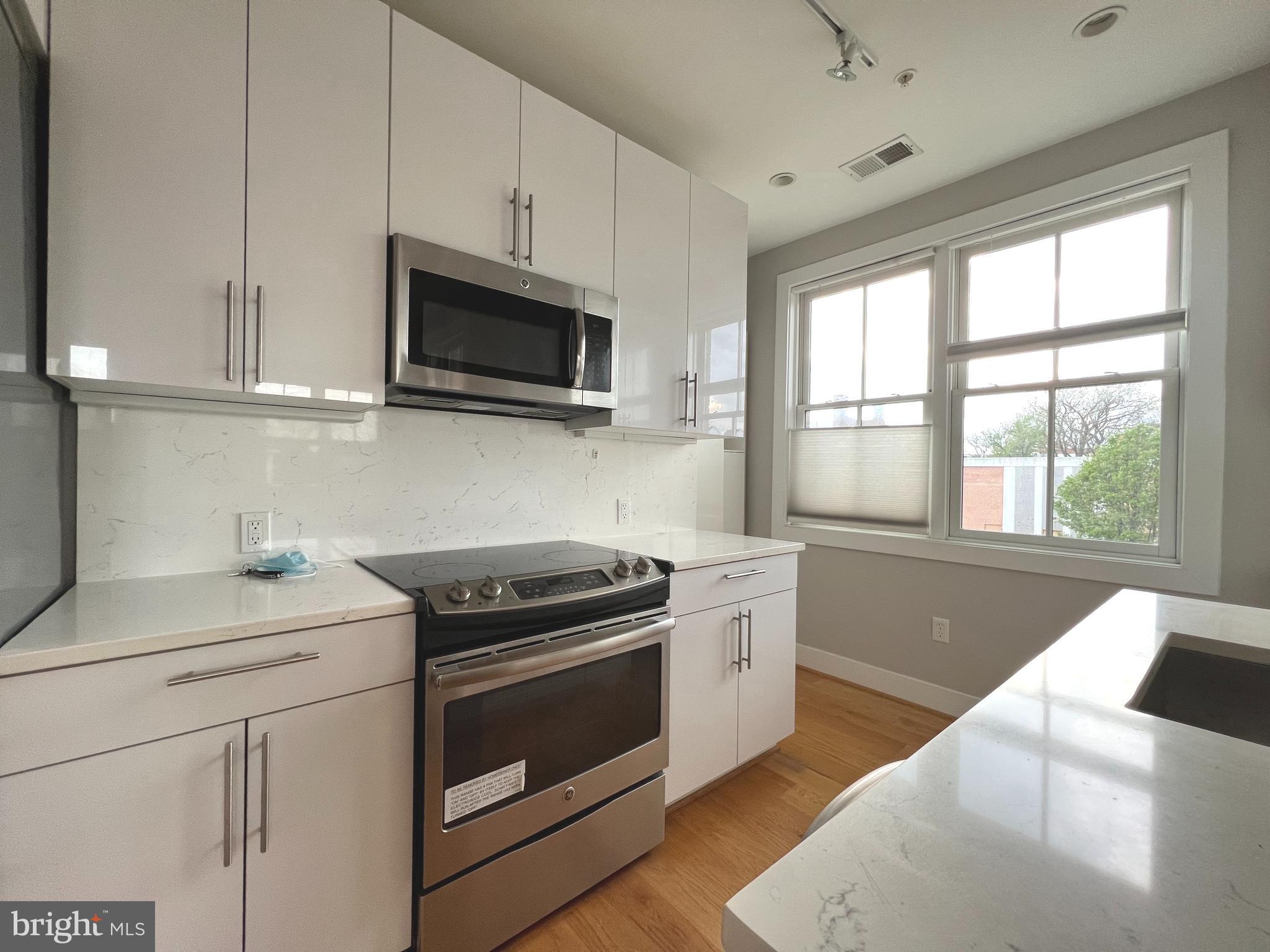 1209 G Street Southeast, Unit 8 Washington, DC 20003 - Photo 16 of 27 a kitchen with stainless steel appliances granite countertop white cabinets granite counter tops and a window
