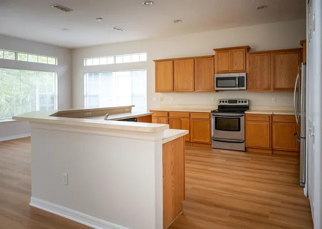 a kitchen with stainless steel appliances granite countertop a sink a stove a refrigerator with grey cabinets