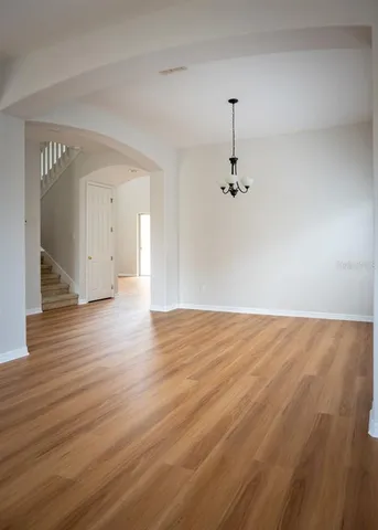 wooden floor in an empty room with a chandelier